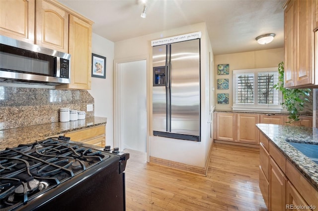 2995 Albion St, Denver, CO 80207 - kitchen featuring backsplash, light wood finished floors, stainless steel appliances, and dark stone countertops