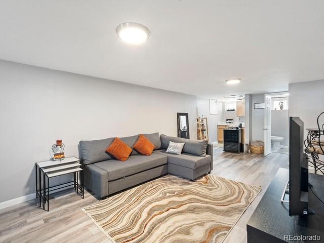 2995 Albion St, Denver, CO 80207 - living room with light wood-style floors, baseboards, and bar area