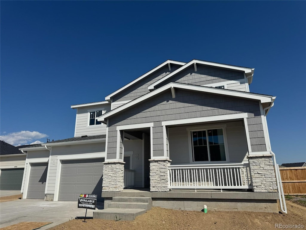 4856 Brangus Dr, Windsor, CO 80528 - craftsman-style house featuring covered porch, stone siding, concrete driveway, and an attached garage