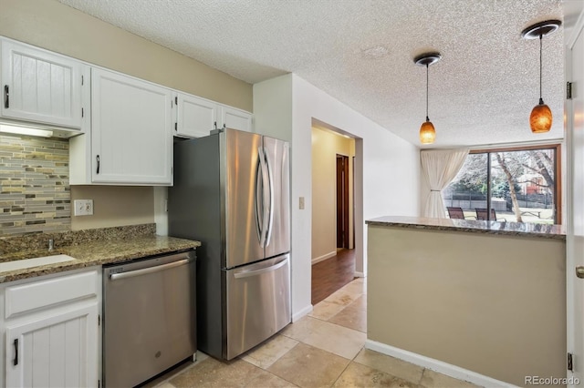 13950 E Oxford Pl Unit B105, Aurora, CO 80014 - kitchen with appliances with stainless steel finishes, a textured ceiling, white cabinets, backsplash, and decorative light fixtures