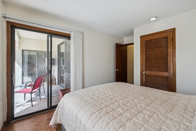 13950 E Oxford Pl Unit B105, Aurora, CO 80014 - bedroom featuring access to exterior, dark wood finished floors, a closet, and a textured ceiling