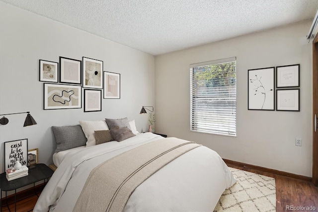 13950 E Oxford Pl Unit B105, Aurora, CO 80014 - bedroom featuring a textured ceiling, wood finished floors, and baseboards