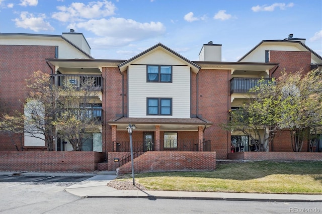 13950 E Oxford Pl Unit B105, Aurora, CO 80014 - view of property with a chimney, a balcony, brick siding, covered porch, and uncovered parking