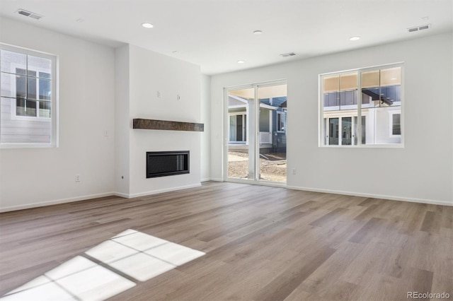 unfurnished living room with a healthy amount of sunlight and light hardwood / wood-style floors