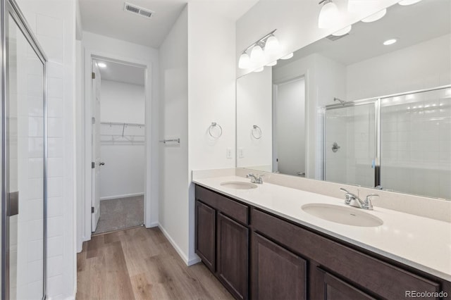 bathroom with wood-type flooring, vanity, and a shower with shower door