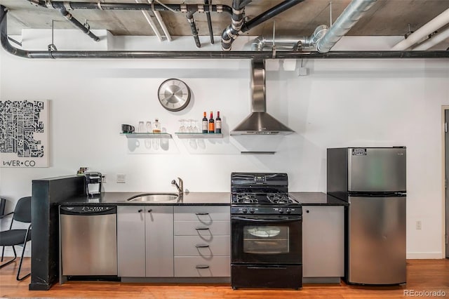 kitchen with sink, light wood-type flooring, wall chimney range hood, and appliances with stainless steel finishes