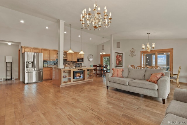 living room featuring light hardwood / wood-style flooring, vaulted ceiling, and a notable chandelier