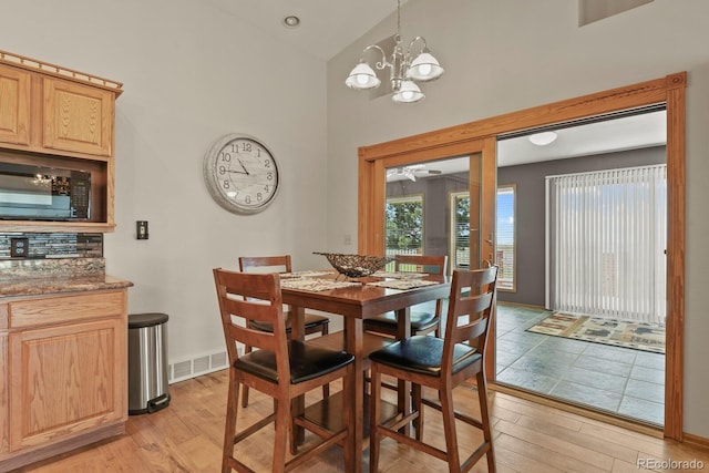 dining area featuring vaulted ceiling, light hardwood / wood-style flooring, and a chandelier