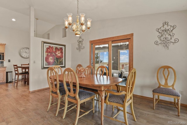 dining area with a notable chandelier, light hardwood / wood-style floors, and lofted ceiling