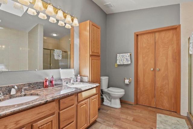 bathroom with hardwood / wood-style floors, vanity, an enclosed shower, and toilet