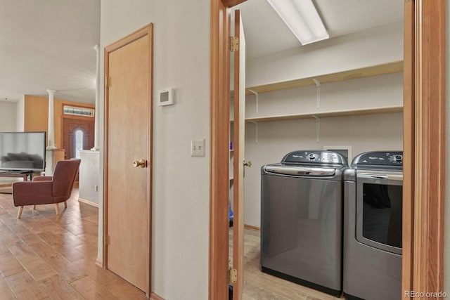 clothes washing area with washing machine and dryer and light hardwood / wood-style floors