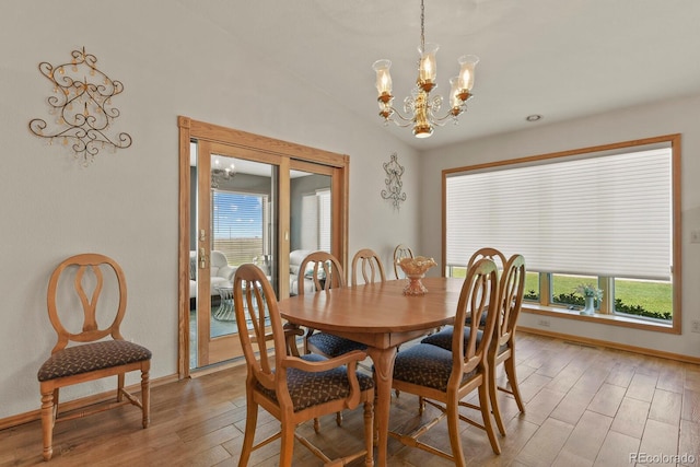 dining space with a notable chandelier, wood-type flooring, and lofted ceiling