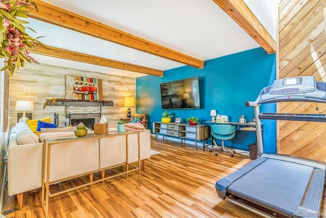 1152 S Yosemite Way Unit 29, Denver, CO 80247 - living room featuring wooden walls, beam ceiling, wood finished floors, and a stone fireplace