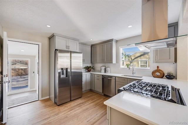 kitchen with sink, island range hood, gray cabinets, and appliances with stainless steel finishes