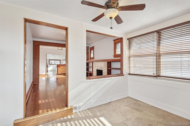 unfurnished room featuring ceiling fan and a fireplace