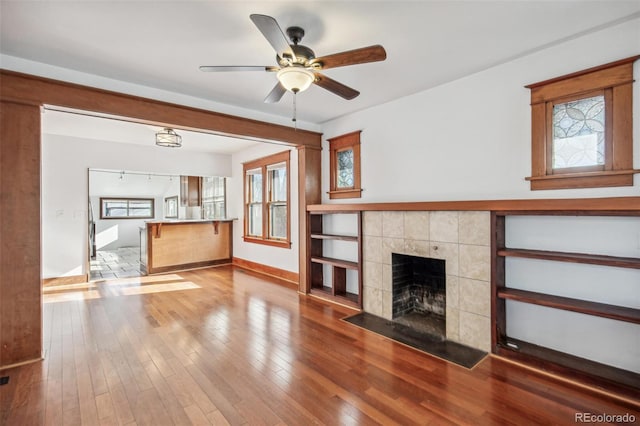 unfurnished living room with a fireplace, ceiling fan, and wood-type flooring