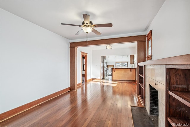 unfurnished living room with a tile fireplace, ceiling fan, and hardwood / wood-style flooring