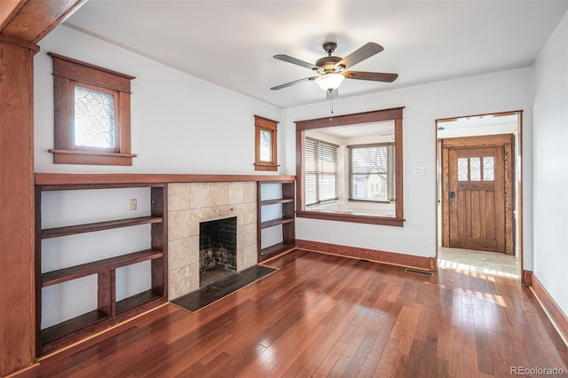 unfurnished living room with a fireplace, ceiling fan, and dark hardwood / wood-style floors