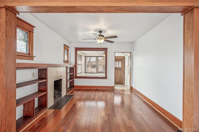 unfurnished living room with ceiling fan, a fireplace, and hardwood / wood-style flooring