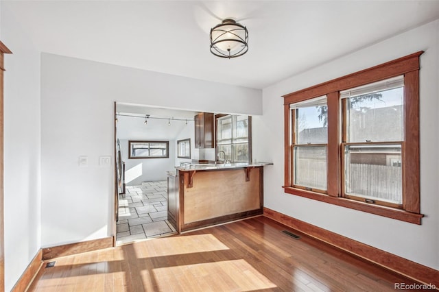 kitchen featuring kitchen peninsula, light wood-type flooring, track lighting, and sink