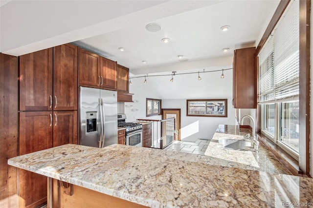 kitchen featuring light stone counters, kitchen peninsula, custom range hood, appliances with stainless steel finishes, and sink