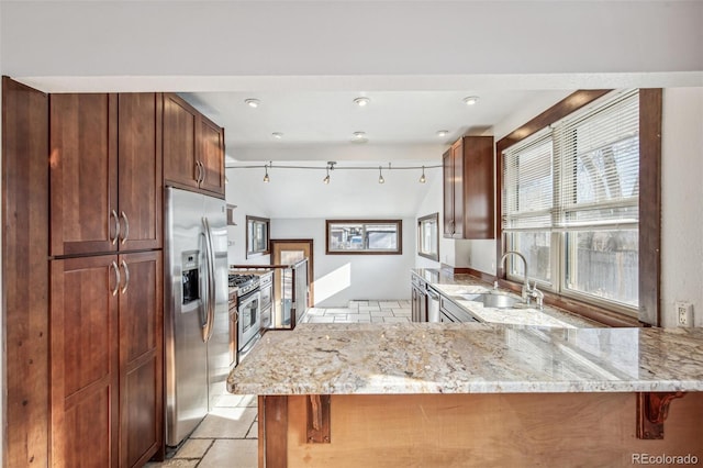 kitchen featuring sink, light stone counters, appliances with stainless steel finishes, and kitchen peninsula