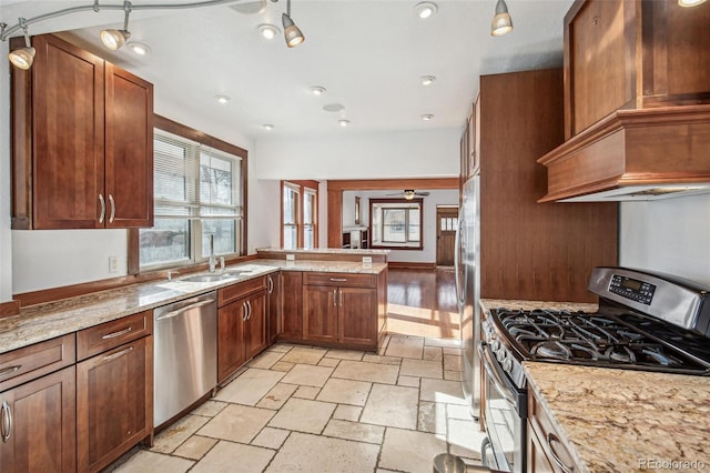 kitchen with light stone countertops, premium range hood, stainless steel appliances, ceiling fan, and sink