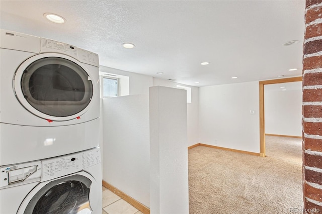 laundry room with a textured ceiling, light colored carpet, and stacked washing maching and dryer