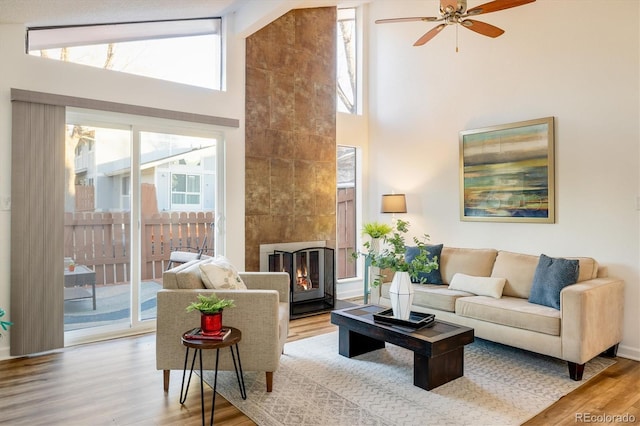 living room featuring light hardwood / wood-style floors, high vaulted ceiling, a wealth of natural light, and ceiling fan