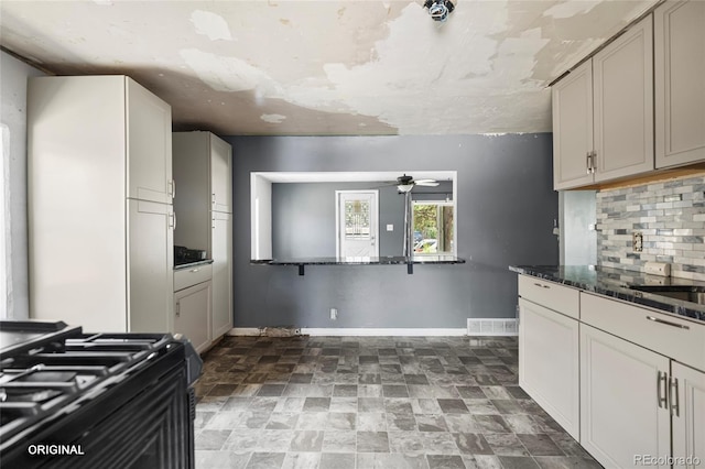 5481 Leyden St, Commerce City, CO 80022 - kitchen featuring a ceiling fan, decorative backsplash, gas range oven, stone finish floors, and dark stone countertops
