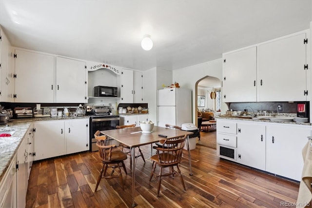 675 Holland St, Lakewood, CO 80215 - kitchen with stainless steel range with electric cooktop, black microwave, freestanding refrigerator, arched walkways, and dark wood-style floors