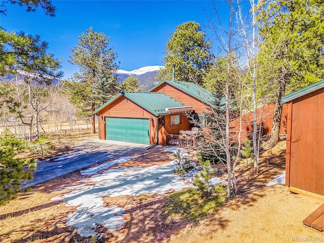 view of side of home featuring concrete driveway, a mountain view, a garage, and metal roof