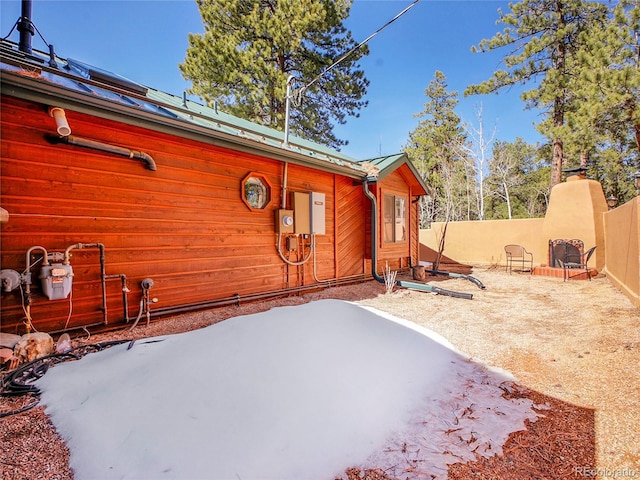 view of side of property with metal roof, a patio, a standing seam roof, and fence