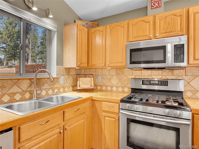 kitchen featuring a sink, backsplash, appliances with stainless steel finishes, and light countertops