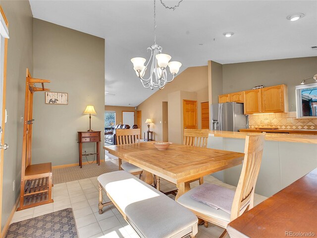 dining space with an inviting chandelier, lofted ceiling, light tile patterned floors, and baseboards