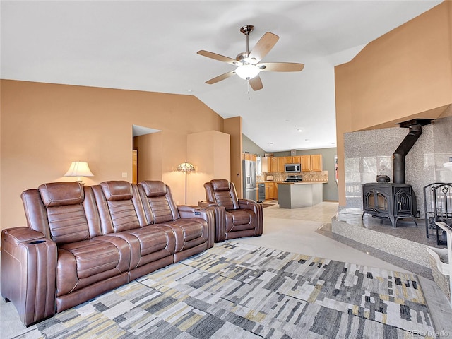 living room with high vaulted ceiling, a ceiling fan, and a wood stove