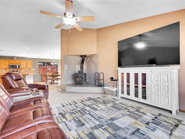 living area featuring a ceiling fan, a wood stove, and vaulted ceiling