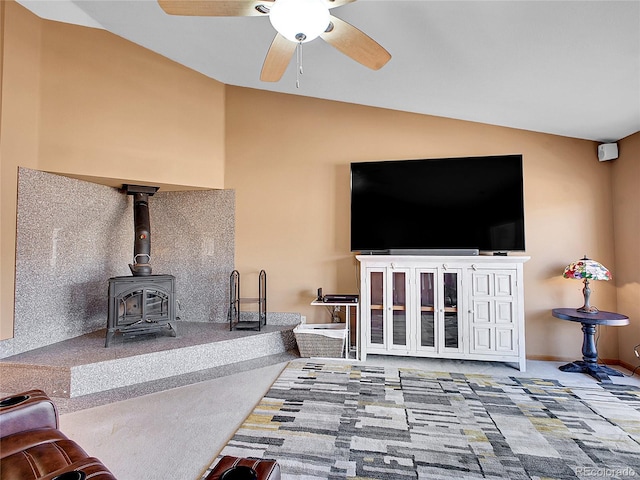 living room with baseboards, lofted ceiling, a ceiling fan, and a wood stove