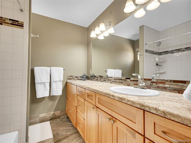 full bathroom with vanity, baseboards, visible vents, a tile shower, and decorative backsplash