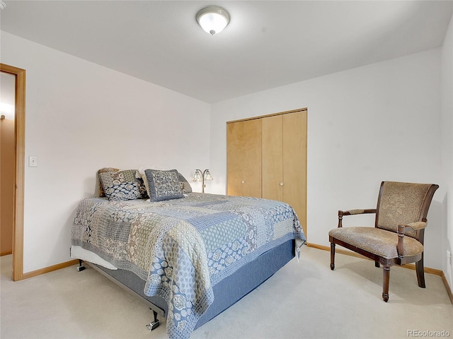 bedroom featuring a closet, light colored carpet, and baseboards