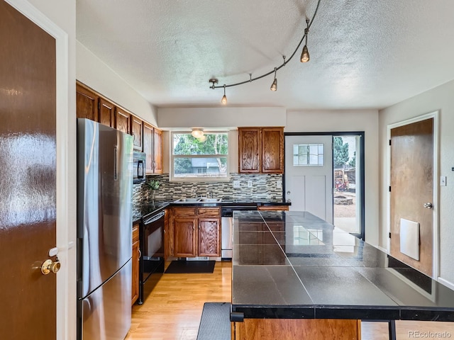 380 S 25th Ave, Brighton, CO 80601 - kitchen with freestanding refrigerator, a textured ceiling, brown cabinets, backsplash, and light wood finished floors