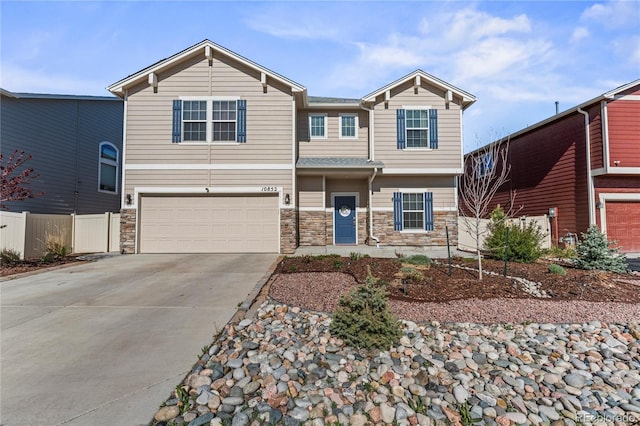 craftsman-style home featuring stone siding, driveway, fence, and a garage