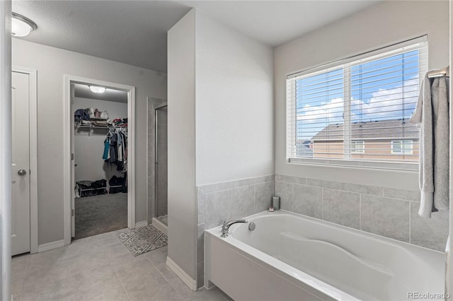 full bath featuring a bath, tile patterned flooring, a shower stall, and a spacious closet