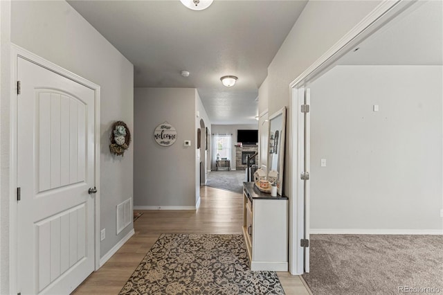 hallway with visible vents, light wood-style flooring, and baseboards