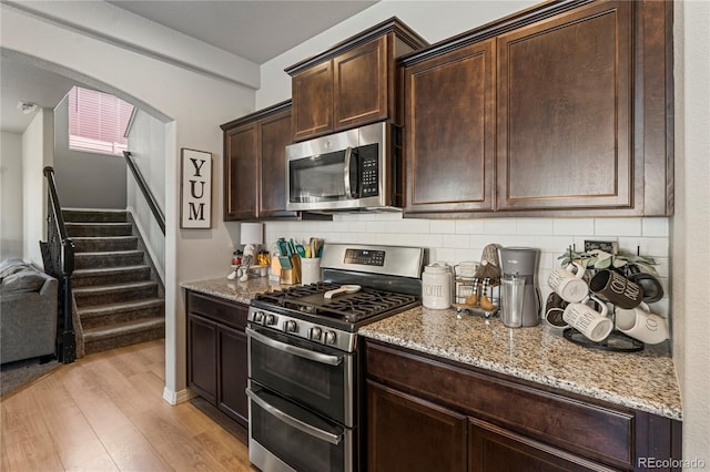 kitchen featuring light wood-style floors, stainless steel appliances, tasteful backsplash, and light stone countertops