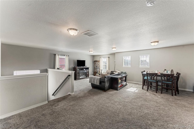 carpeted living room with a textured ceiling, visible vents, and baseboards