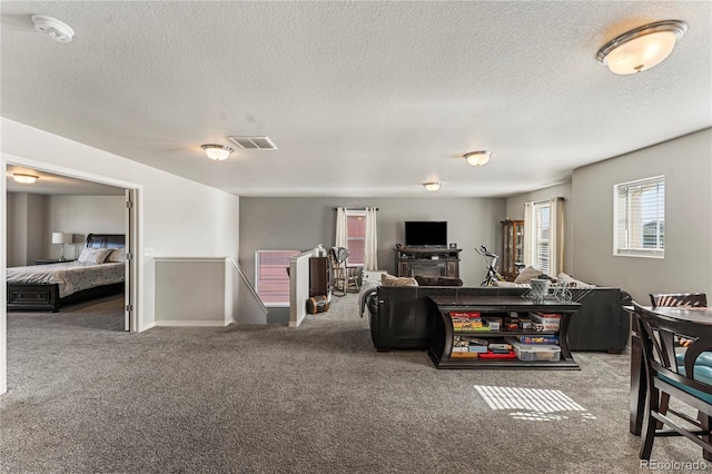 living room with a textured ceiling, visible vents, and carpet floors