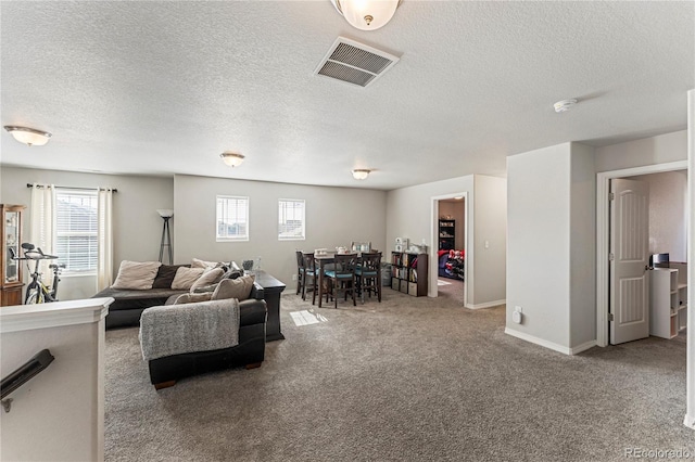 living area featuring carpet, a textured ceiling, visible vents, and baseboards