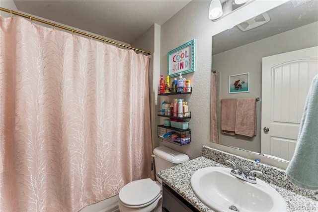 bathroom featuring toilet, curtained shower, vanity, and a textured wall