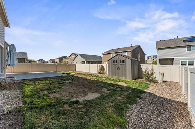view of yard with a patio, a residential view, a storage unit, a fenced backyard, and an outbuilding
